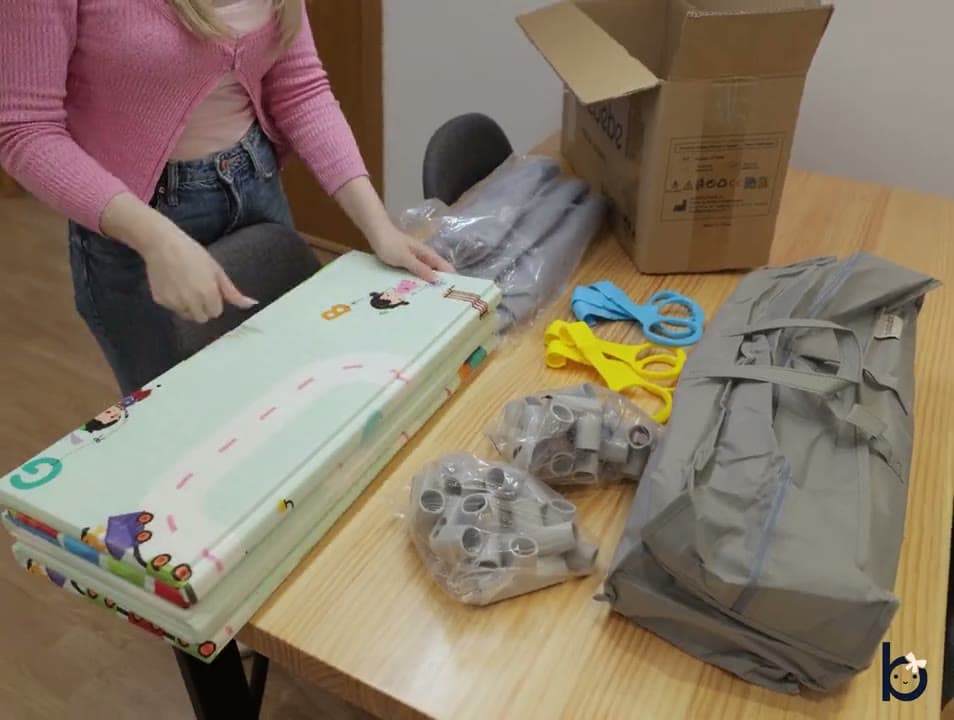 Todo el contenido de la caja: estructura, tela, alfombra, bolas, canasta, libro y bolsa